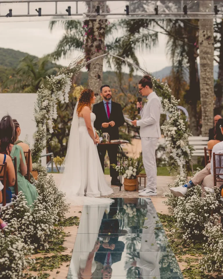 Corredor da cerimônia com flores e os noivos no altar ao fundo